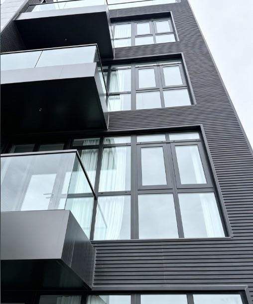Close exterior view of black-framed windows and glass balcony guards on a modern building