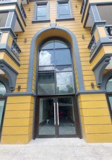 Historic yellow facade with a tall arched window and glass entrance