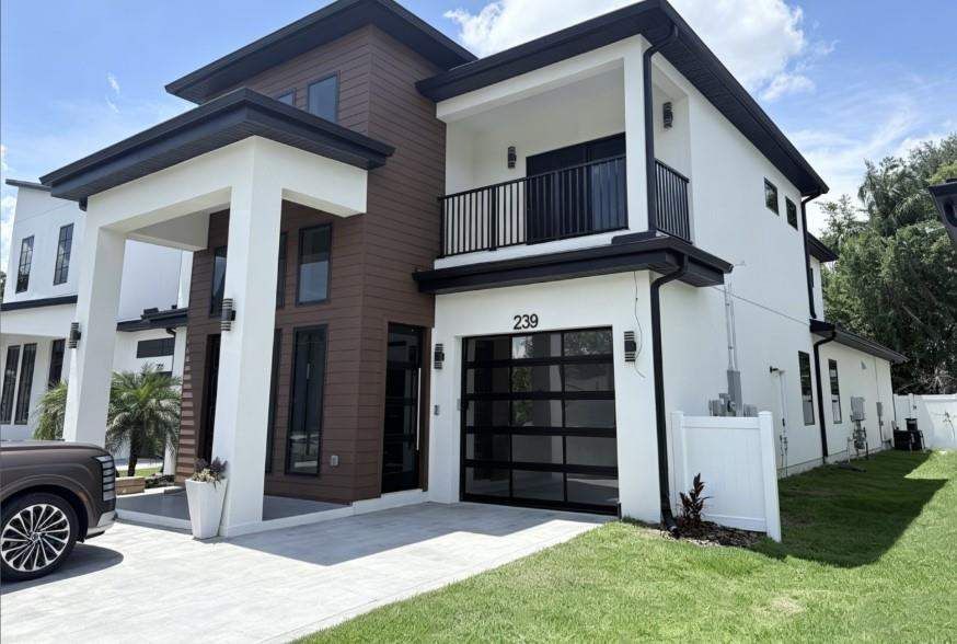 Full view of a modern two-story residence with impact windows and a glass garage door