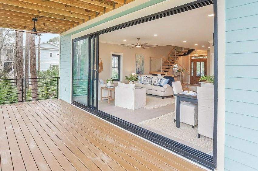 Large sliding glass wall opening from a wood deck into a residential living space
